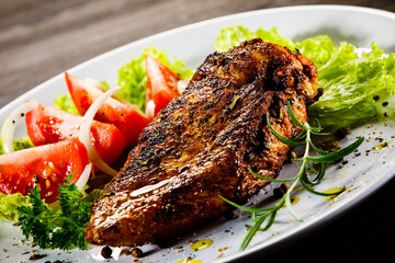 Grilled chicken fillet and vegetables on wooden background