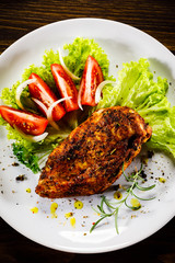 Grilled chicken fillet and vegetables on wooden background