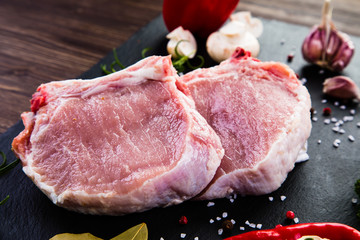 Raw pork chops on cutting board and vegetables