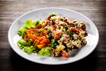 Grilled meat, white rice and vegetables on wooden table