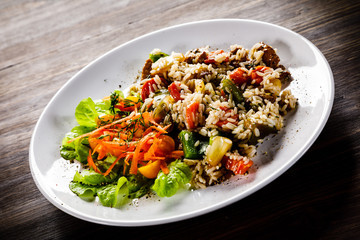 Grilled meat, white rice and vegetables on wooden table