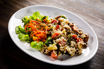 Grilled meat, white rice and vegetables on wooden table