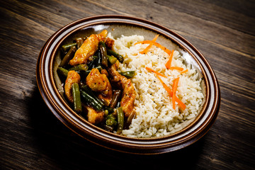 Grilled meat, white rice and vegetables on wooden table