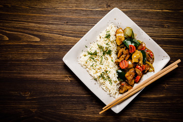 Grilled meat, white rice and vegetables on wooden table