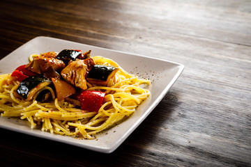 Roasted meat, pasta and vegetables on wooden background