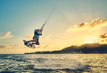 Fototapeta Young man kite boarder jumps over the sea at sunset            obraz