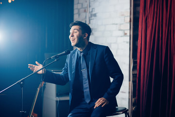 Stand up comedian on stage. Young man talks joke into microphone or sings songs