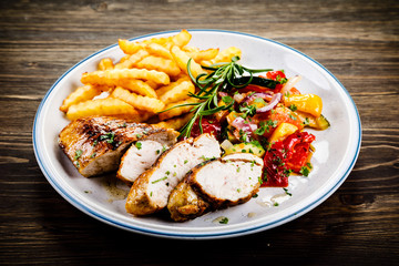 Grilled chicken fillet with french fries on wooden background