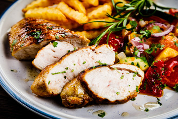 Grilled chicken fillet with french fries on wooden background