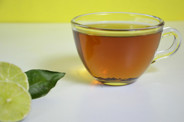 Transparent cup and teapot with black tea, dry tea brewing on the table, bergamot slices, or lemon or lime on a white background