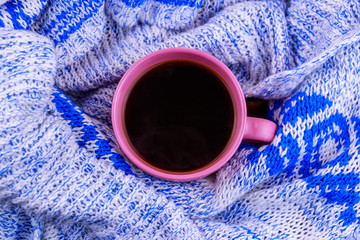 Cup of coffee on cozy knitted sweater