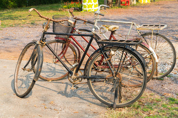 Fototapeta na wymiar Old and rusty bicycles are on display at the roadside as part of decoration objects in the park, selective focus and copy space.