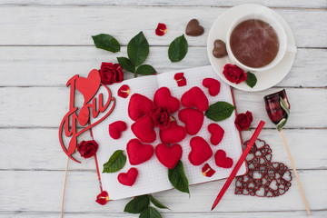 Valentines day. Notebook on a white wooden table with red hearts. Romantic morning on the day of lovers. Top view