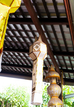 Traditional lanterns made from paper and cotton material hanging under the roof in front of the house depicting an ancient decoration style in northern Thailand.