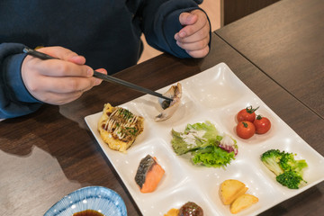 Young girl eating breakfast in the hotel with chopsticks