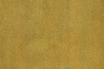 old yellow wall with small black spots. rough surface texture