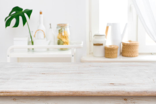 Wooden table top on blurred kitchen window and shelves background