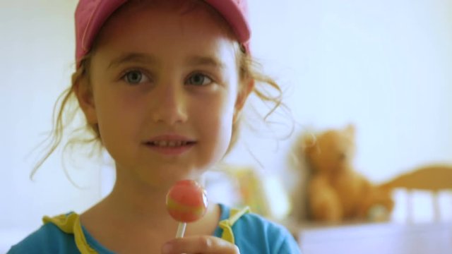 Little girl enjoying a lollipop while staring at camera. Child eating candy, sweets, sugar