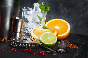 Cocktail making concept. Cold bar utensils with fresh ingridients and ice on dark background. Copy free space for text, logo or brand.