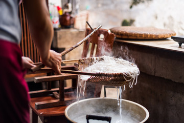 Woman preparing rice noodles traditionally at home