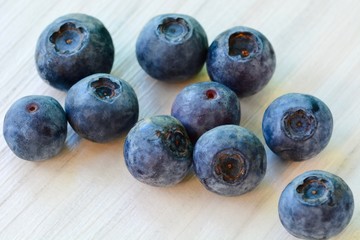 Close-up photo of fresh ripe blueberries on white wooden background