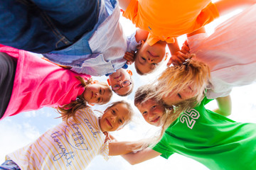 A huddle of school kids looking down at camera,
