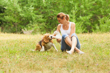 Young woman playing with her pets sitting on grass