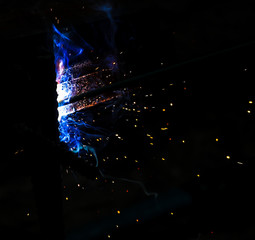 Flame of fire and sparks from welding metal at night