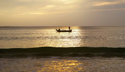 Obraz premium Silhouette Fishing Boat in Evening, Water Sea Reflect Sunlight Before Sunset 
