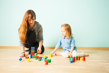 Naklejka premium Young teacher sitting on a floor communicating with her pupil