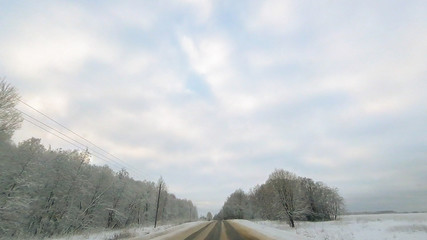 Country road in winter along the forest with white snow trees