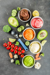 Trendy vegan food, summer healthy dessert concept, colorful diet vegetable ice cream with avocado, cucumber, tomato, beet, carrot, broccoli, cauliflower. Frozen veggie smoothie, black background
