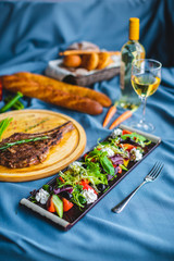 beef steak with salad, bread and wine on the table