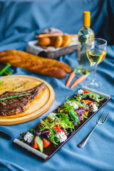 beef steak with salad, bread and wine on the table