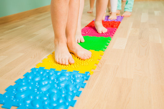 Closeup of kid feet while standing on special massaging mat