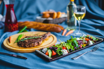 beef steak with salad, bread and wine on the table