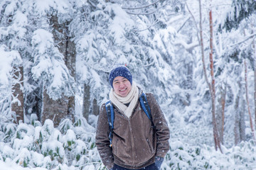 Fototapeta na wymiar Portrait of Asian man with blue wool hat feeling very happy bit cold under snowy weather in Japan Alp.