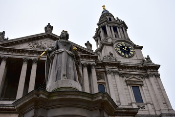 Fototapeta na wymiar St Pauls Cathedral. Facade closeup with Queen Anne statue and tower with golden clock. London, United Kingdom, Christmas.