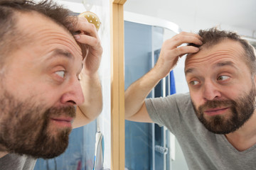Obraz premium Happy adult man looking at hair in mirror