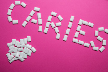 Gum in the form of caries lettering on a pink background