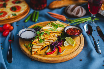 quesadilla with sauce and lemon on a wooden plate