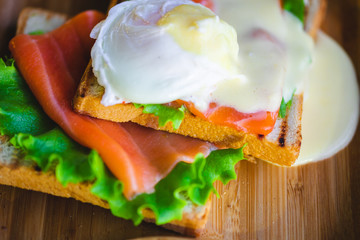 sandwich with salmon and egg on a wooden plate. breakfast