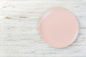 Directy above Empty pink matte plate on white wooden background with copy space