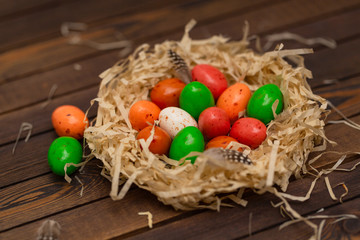 Colorful Easter egg in the nest on wood background. Top view with copy space