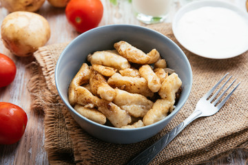 Homemade potato gnocchi in a plate. Raw Italian dumplings on a floured wooden board in a kitchen