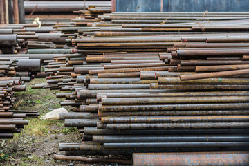 Metal rolling. A round tube are stacked in storage for sale and loading in stock in the open air. Close-up.