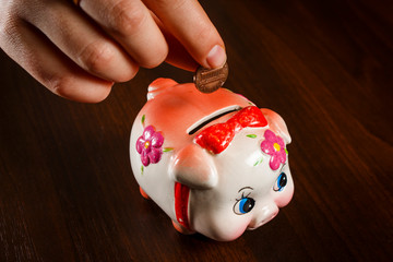 The girl throws a coin in the piggy bank