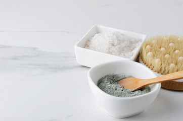 Closeup of white face clay,bath salt and body brush on marble white table