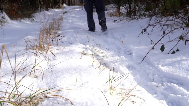 Man walks in the snow. Snow covered trail close-up. Hiking in a sunny cold winter day.
