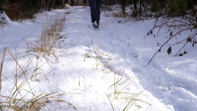 Man walks in the snow. Snow covered trail close-up. Hiking in a sunny cold winter day.
